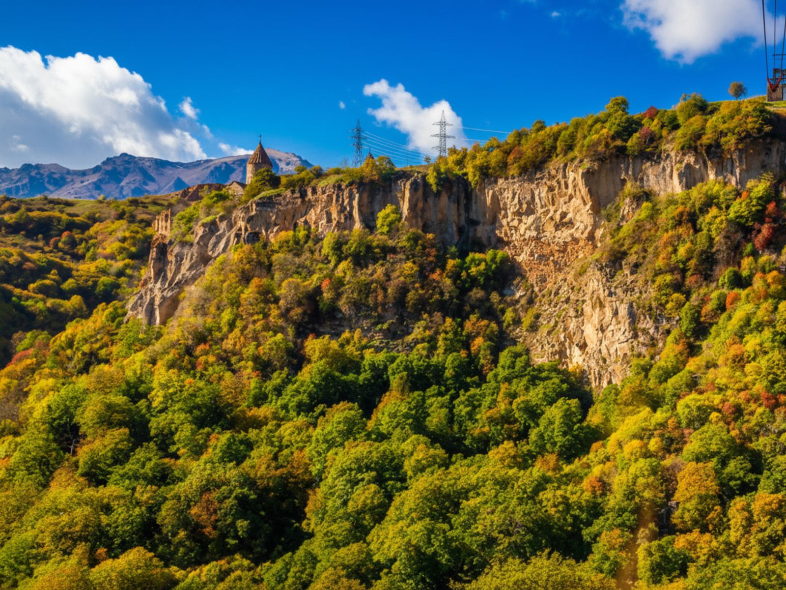 Панорамный вид с обрыва: вдалеке Татевский монастырь и горные пейзажи, ущелье 