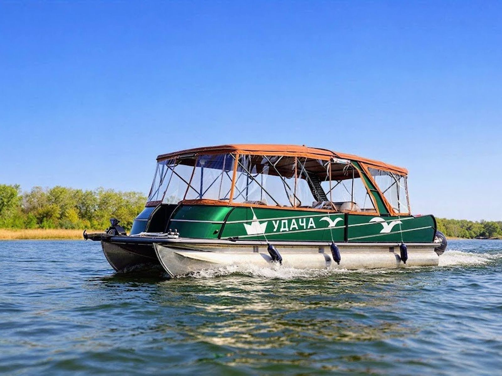 Прогулочный понтонный катер «Удача» идет по реке Дон на фоне живописной природы левого берега Ростова-на-Дону 